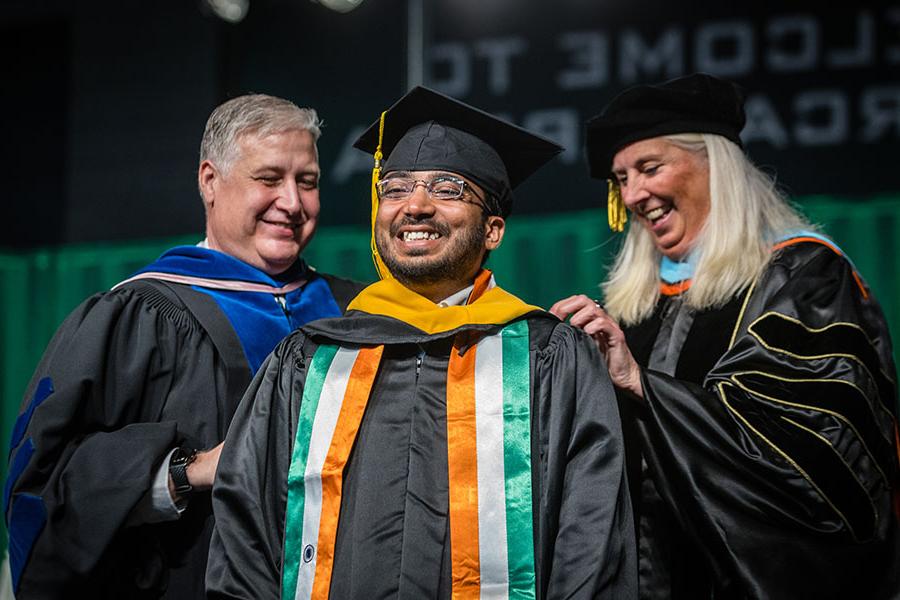 Provost Dr. Jamie Hooyman and Dr. Greg Haddock, associate provost of graduate studies and special programs, place a master's degree hood on a Northwest graduate.
